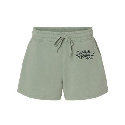 Front view of sage green Born & Raised Shorts with 2025 script logo and drawstring waistband